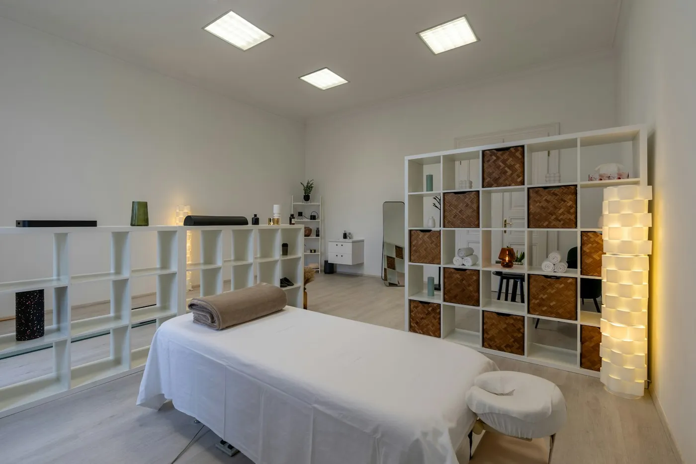 A bright white clinic treatment room with a prepared treatment bed