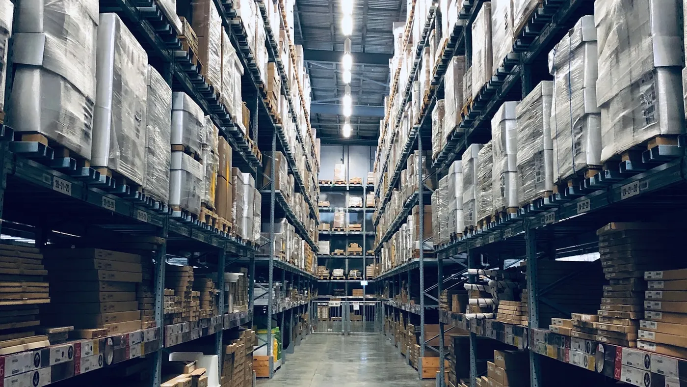 A tall warehouse aisle stacked with shrink-wrapped pallets and boxes ready for dispatch